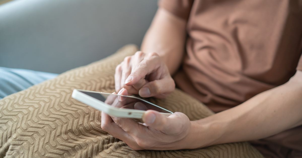 Una signora sorridente consulta il proprio smartphone per scoprire come controllare i punti patente tramite l'app ufficiale.